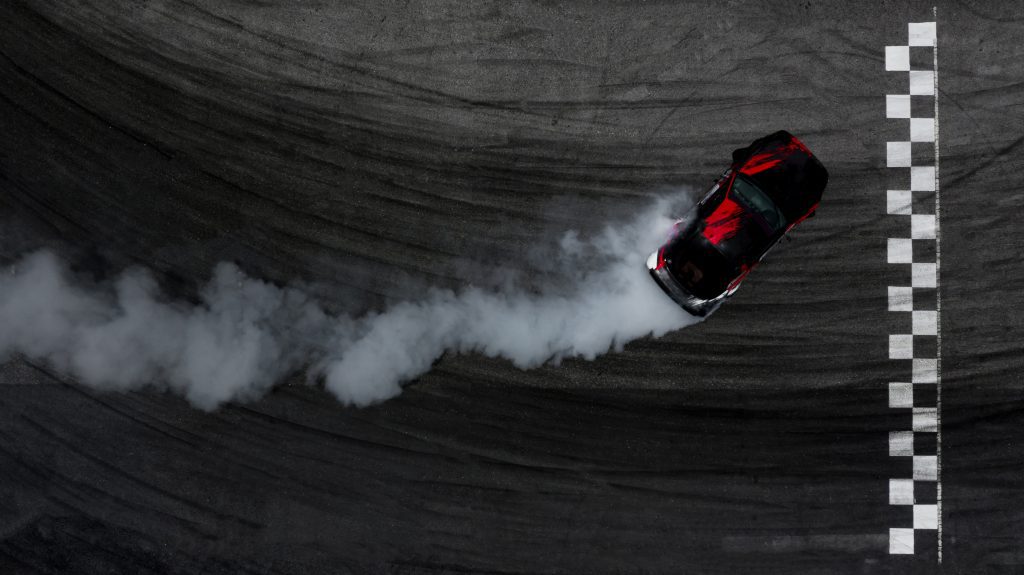 Aerial top view car drifting on race track with finish line and